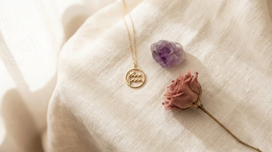 Goldener Wassermann-Sternzeichenanhänger neben Amethyst auf hellem Leinen