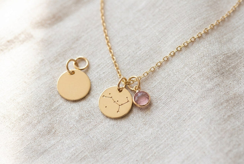 Goldfarbene Gliederkette mit zwei Anhängern nebeneinander, daneben ein loser dritter Anhänger mit derselben Öse